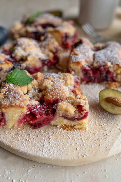 Plum crumble cake served sliced on a wooden platter