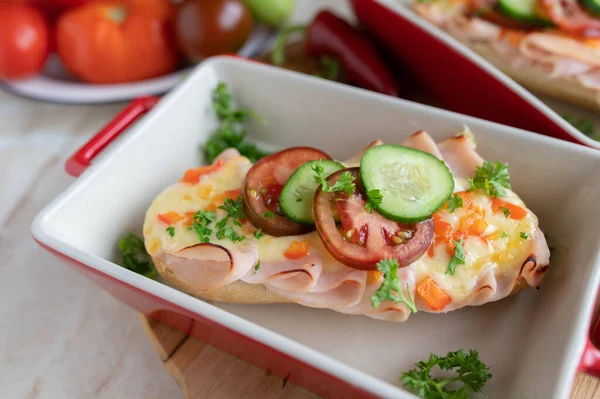 Baked Ham and cheese sandwich on a baguette bun with vegetables