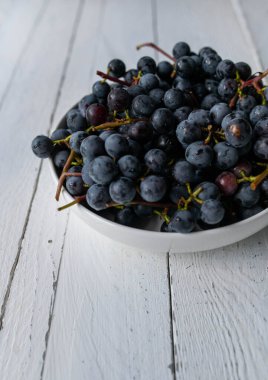 Taze toplanmış siyah üzümlü bir kase, beyaz arka planda izole edilmiş ve kopyalama alanı olan.