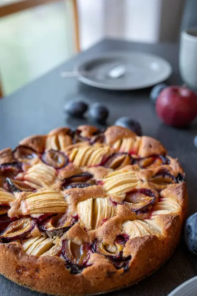 Homemade apple cake with plums on a table
