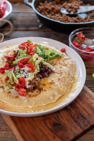 Mexican pancakes with meat and vegetables  on a wooden table