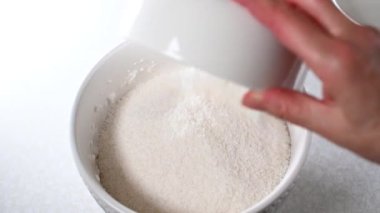 Rendelenmiş hindistan cevizini çırpılmış yumurta beyazıyla bir kaseye koy ve hindistan cevizli kurabiye için hamur karıştır.