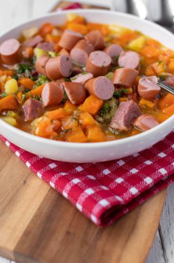 Lezzetli ev yapımı havuç çorbası ya da domuz eti ve Viyana sosisi ile güveç. Sıcak servis edilmiş ve hafif arka planda izole edilmiş kaşıkla derin tabakta yemeye hazır. Yakın çekim.