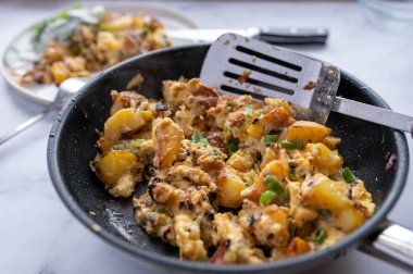 Kızarmış patates, omlet, soğan ve soğan kızartma tavasında.