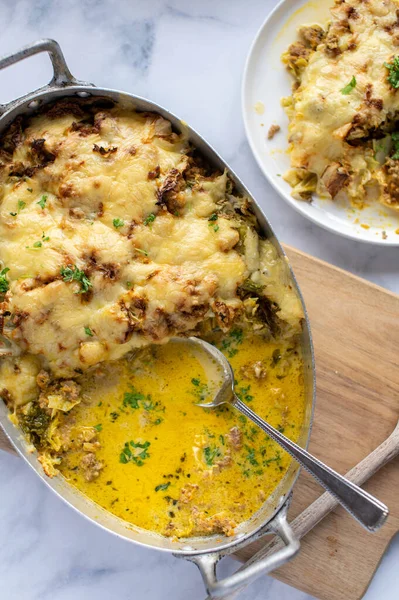 Delicious winter food with a oven baked casserole made with minced meat, savoy cabbage, vegetables and cheese. Served in a delicious sauce in a baking pan. Closeup