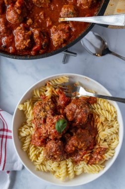 Lezzetli ev yapımı et, İtalyan köftesi, domates sosu ve fusilli makarna. Hafif mutfak arka planında çatallı bir tabakta yemeye hazır. Üst görünüm