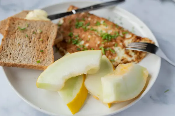 Healthy protein breakfast with egg white omelet, whole wheat toast and honey melon for sports nutriton, bodybuilding, dieting or healthy eating background.