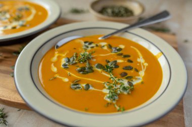 Tabakta kabak çekirdeği ile ev yapımı taze kabak çorbası. Lezzetli vejetaryen çorbası. Masada garnitür ve kaşıkla yemeye hazır. Yakın çekim..