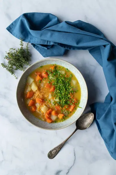 Bowl with healthy vegan soup. Cooked with carrots, ,kohlrabi and red lentil risoni on light background with copy space. Food background for Healthy eating, vegan and vegetarian food