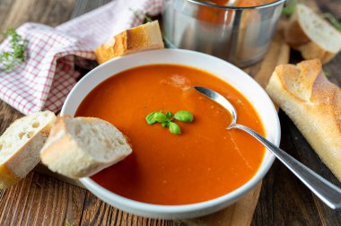 Ev yapımı baget ekmekli domates çorbası. Tahta arka planda kaşık var. Yakın çekim.