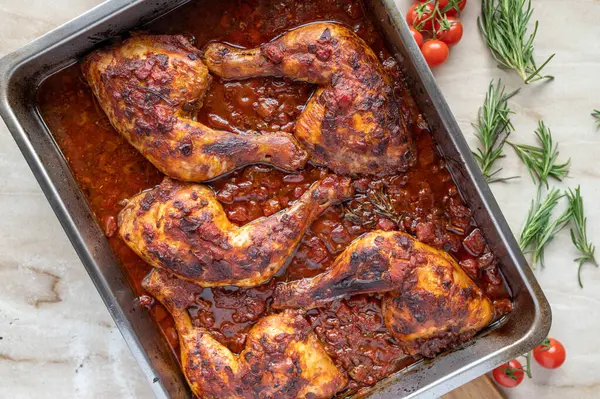 Braised chicken legs with italian red wine tomato sauce in a roasting pan. Italien cuisine.