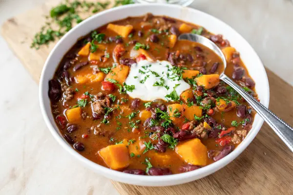 Delicious sweet potato soup with kidney beans, minced meat and vegetables. Gluten free and low fat meal on light background