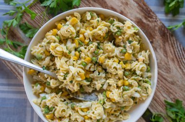 Bezelye, mısır, jambon, mayonez ve bitkilerle ev yapımı makarna salatası. Lezzetli yaz ve barbekü mezesi