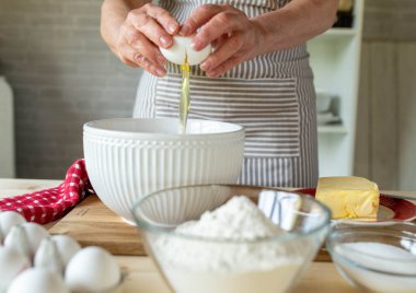 Hamur ya da hamuru yapmak için kırık çiğ yumurtayı kaseye koy. Yumurta beyazı kabuktan çıkıp bir kaseye giriyor..