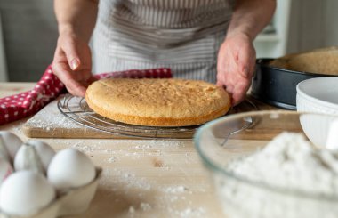 Mutfaktaki kadınlar tarafından soğutma rafına taze pişmiş kek kalıbı koymak. Ön görünüm