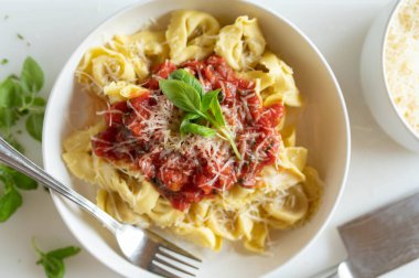 Taze domates soslu Tortellini ve tabakta rendelenmiş parmesan peyniri.