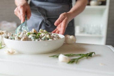 Önlüklü kadın mutfakta taze ve sağlıklı patates salatası hazırlıyor.