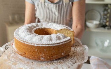 Taze pişmiş sarı sünger keki ya da mutfakta önlüklü bir kadının servis ettiği kek..