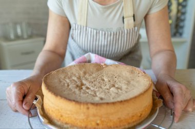 Mutfakta taze pişmiş sünger kek tabağı olan bir kadın.