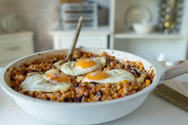 Kızartma tavasında yumurta soslu sağlıklı pirinç yemeği. Basmati pilavı, fasulye, mısır, biber, soğan, domates ve bitkilerle pişirilir.