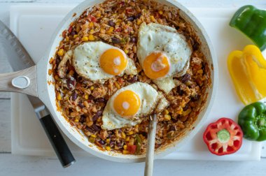 Kızartma tavasında yumurta soslu sağlıklı pirinç yemeği. Basmati pilavı, fasulye, mısır, biber, soğan, domates ve bitkilerle pişirilir.