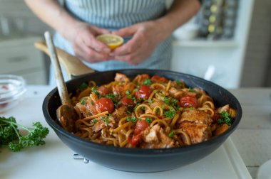 Pan fried salmon with creamy tomato sauce an spaghetti in a skillet on kitchen counter. Ready to eat