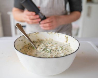 Mutfakta yeni hazırlanmış ev yapımı tartar sosu ya da remoulade ile bir kadın var.