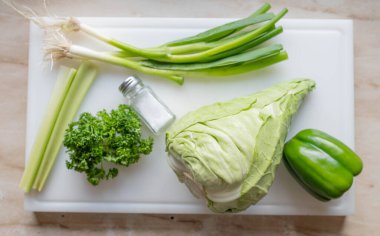 Lahana, yeşil biber, maydanoz, kereviz ve taze soğan ile lahana salatası yapmak için gerekli malzemeler.