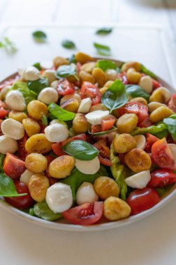 Domatesli Caprese Salatası, mozzarella, kızarmış gnocchi ve fesleğen. Mutfak tezgahındaki tabakta yemeye hazır..