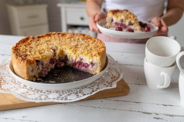 Vanilyalı puding ve badem soslu lezzetli bir vişneli pasta servis eden kadın.