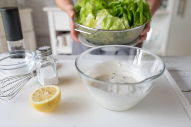 Kadın mutfakta yeşil marul için ev yapımı salata sosu hazırlıyor.