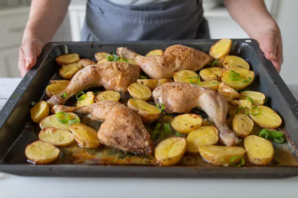 stock image Homemade food, with oven roasted chicken legs and potatoes prepared by womans hands in the kitchen