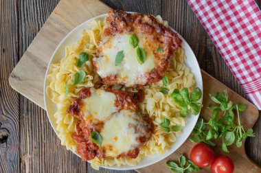 Rustic italian cuisine with oven baked and gratinated cutlets with mozzarella cheese and tomato sauce clipart