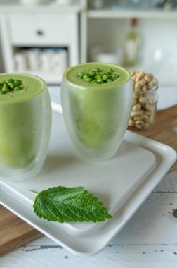 Vejetaryen yeşil bezelye çorbası taze ve ev yapımı. Lezzetli bir yaz yemeği için soğuk servis edildi mutfak tezgahında bardaklarda.