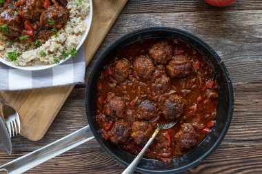 Meatballs in a delicious spicy sauce. Served with brown rice. Homemade food on rustic and wooden table background clipart