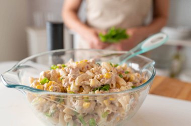 Ton balığı ve mısırlı ev yapımı makarna salatası. Mutfak tezgahındaki cam kasede yemeye hazır.