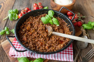 Original Ragu alla Bolognese in a casserole on rustic and wooden table background. Italian cuisine