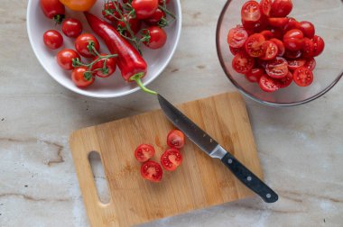 Kesme tahtasında bıçakla kesilmiş kiraz domatesleri.