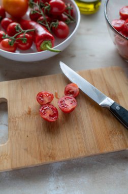 Halved cherry tomatoes on a cutting board with knife. Preparing tomatoes clipart