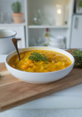 Homemade potato pumpkin soup on a white deep plate on kitchen counter background clipart