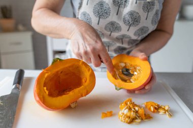 Woman preparing a hokkaido pumpkin or squash in the kitchen clipart