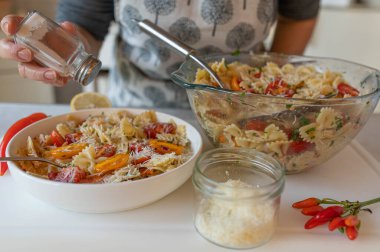 Mutfakta parmesan peynirli ev yapımı makarna salatası olan kadın.