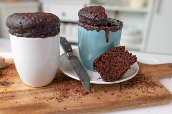 Домашние пирожные с микроволновой печью подаются в кружках на кухонном столе