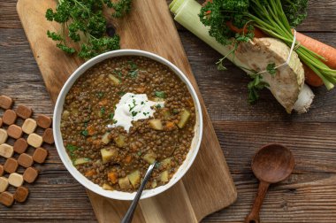 Sağlıklı vejetaryen mercimek çorbası ya da ahşap masa arkasında ekşi kremalı mercimek yahnisi.