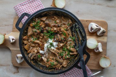 Zrcher geschnetzeltes with turkey breast in a  delicious mushroom sauce with  roasted onions and sour cream in a pan clipart