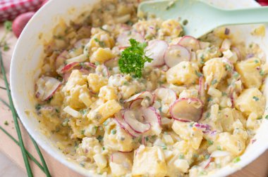 Yoğurt soslu sağlıklı patates salatası, soğan, kırmızı turp, soğan ve turşu.