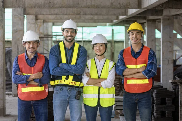 安全ベストとヘルメットを着用して建設現場で一緒に笑みを浮かべてエンジニア 建築家 労働者と安全管理者の多様性チームの肖像 — ストック写真