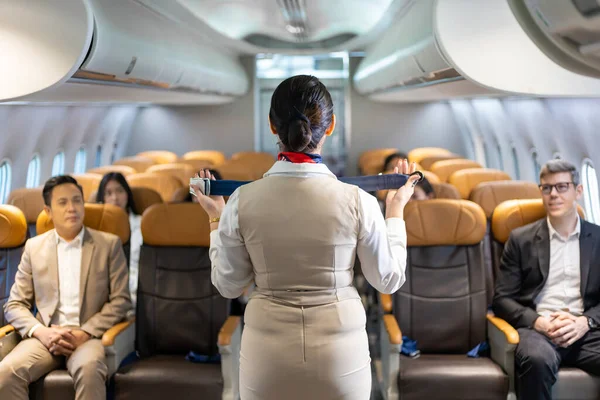 Asian flight attendant is demonstrating safety procedure using seat belt before taking off in the airplane for cabin crew and airline business