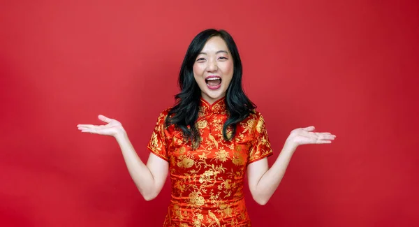 Asian chinese woman with red cheongsam or qipao exciting and laughing for wishing the good luck and prosperity in Chinese New Year celebration holiday isolated on red background