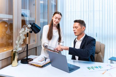 Kafkas iş adamı ve sekreteri, iş dünyası takım yönetimi için sevinçli pazarlama ekibinin artan satış raporuna bakıyor.